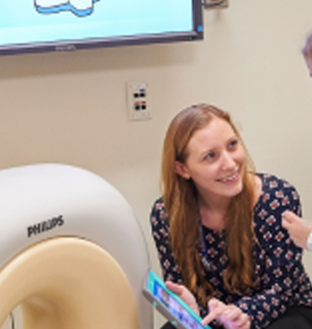 A Stony Brook Child Life Specialist demonstrating a mock CT machine