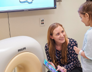 A Stony Brook Child Life Specialist demonstrating a mock CT machine