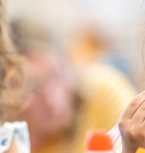 A girl snacking on a carrot stick in school, following a healthy habit.