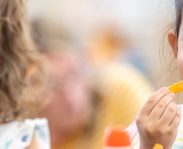 A girl snacking on a carrot stick in school, following a healthy habit.