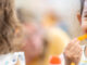 A girl snacking on a carrot stick in school, following a healthy habit.