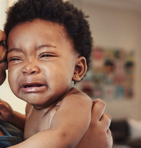 A mother holding her crying baby, who is showing signs of concussion.