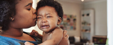 A mother holding her crying baby, who is showing signs of concussion.