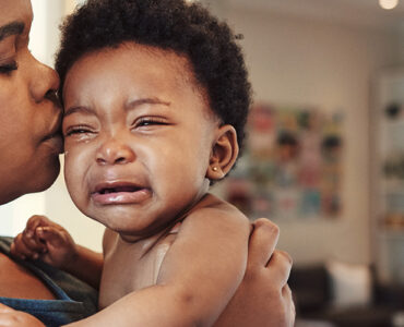 A mother holding her crying baby, who is showing signs of concussion.