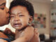 A mother holding her crying baby, who is showing signs of concussion.