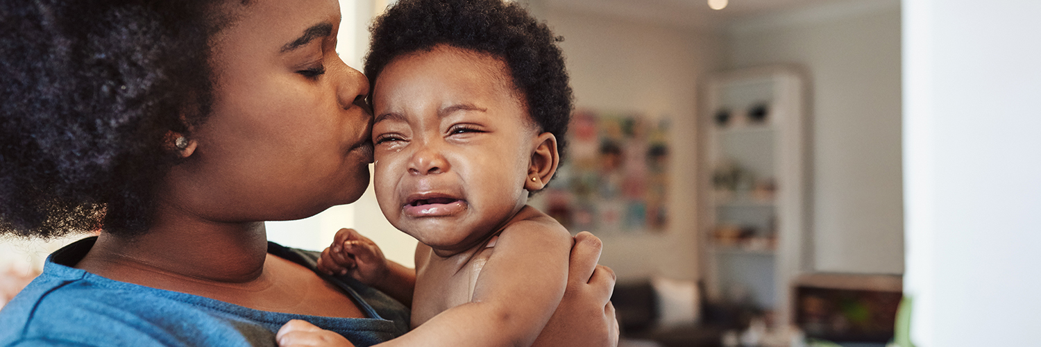 A mother holding her crying baby, who is showing signs of concussion.