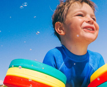 A father practicing swim safety with his son while swimming in the ocean.