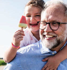 A grandfather, who is at a higher risk of prostate cancer because of his age, carrying his granddaughter.