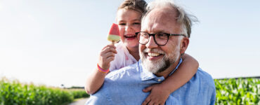 A grandfather, who is at a higher risk of prostate cancer because of his age, carrying his granddaughter.