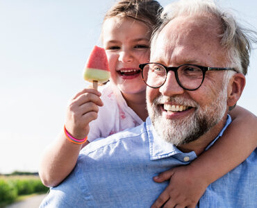 A grandfather, who is at a higher risk of prostate cancer because of his age, carrying his granddaughter.