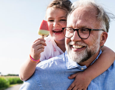 A grandfather, who is at a higher risk of prostate cancer because of his age, carrying his granddaughter.