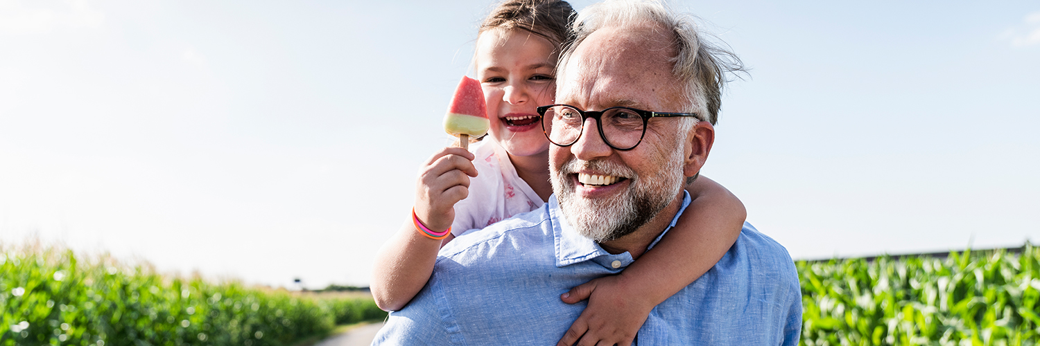 A grandfather, who is at a higher risk of prostate cancer because of his age, carrying his granddaughter.