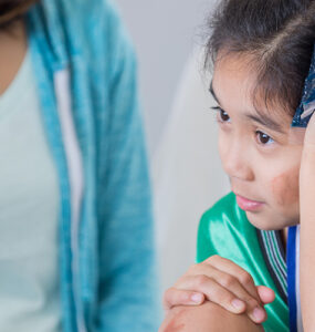 A girl in the emergency room, seeing a doctor for care after hurting herself at a soccer game.