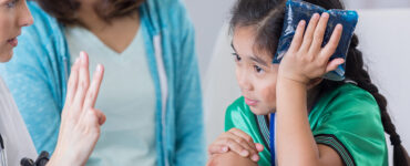 A girl in the emergency room, seeing a doctor for care after hurting herself at a soccer game.