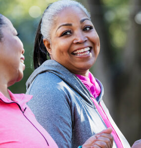 Two middle-aged women walking for exercise, smiling at one another.