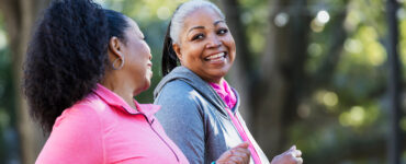 Two middle-aged women walking for exercise, smiling at one another.
