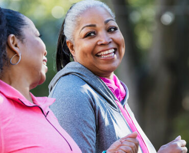 Two middle-aged women walking for exercise, smiling at one another.