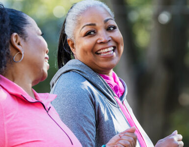 Two middle-aged women walking for exercise, smiling at one another.