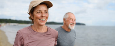 An older woman and man getting exercise on the beach.