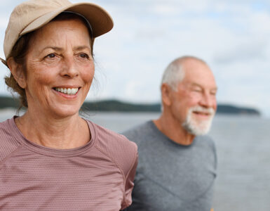 An older woman and man getting exercise on the beach.