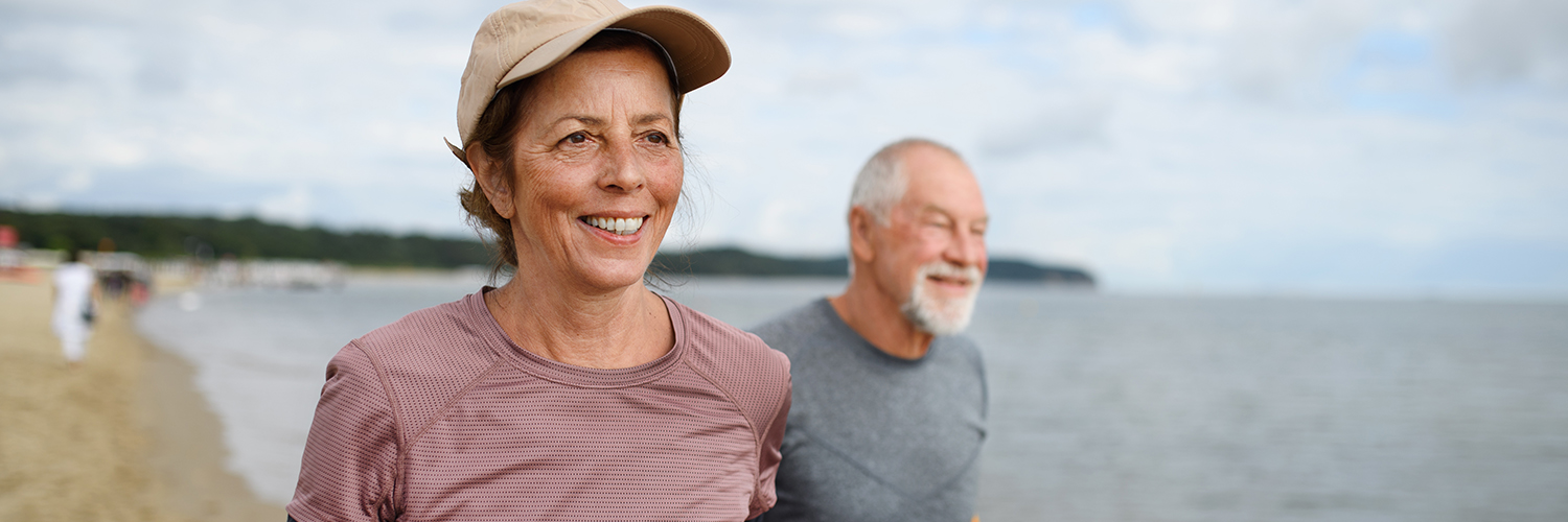 An older woman and man getting exercise on the beach.