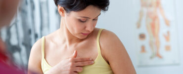 A woman speaking to her doctor about breast lumps as part of her breast cancer screening.