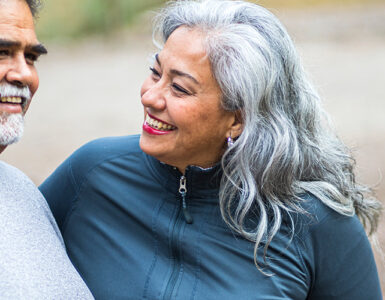 A middle-aged woman sitting on a bench with her husband, smiling at him.
