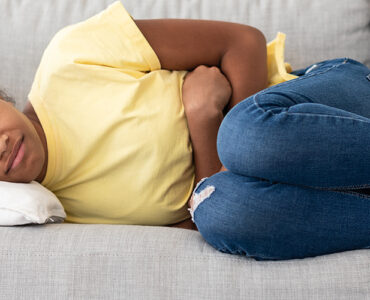 A child curled up on the couch in pain, showing signs of appendicitis.