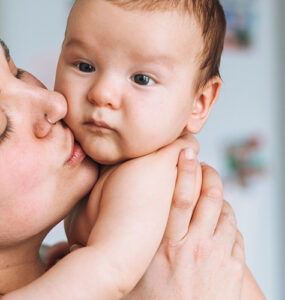 A mother holding her baby, who may need tongue tie surgery due to feeding issues.