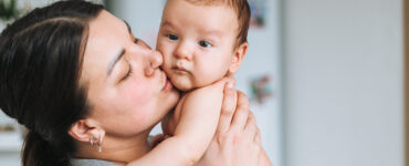 A mother holding her baby, who may need tongue tie surgery due to feeding issues.