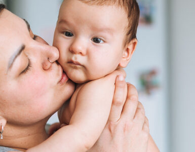 A mother holding her baby, who may need tongue tie surgery due to feeding issues.