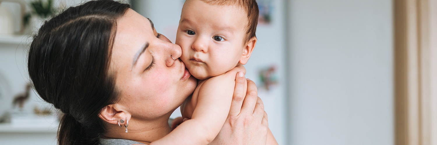 A mother holding her baby, who may need tongue tie surgery due to feeding issues.