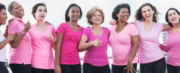 A group of women standing together during a breast cancer awareness walk, wearing pink shirts.