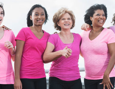 A group of women standing together during a breast cancer awareness walk, wearing pink shirts.