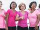 A group of women standing together during a breast cancer awareness walk, wearing pink shirts.