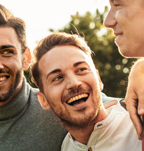 A group of men laughing together outdoors, taking protective measures against mpox in their private lives.