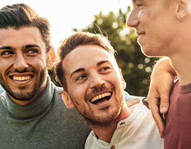 A group of men laughing together outdoors, taking protective measures against mpox in their private lives.