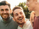 A group of men laughing together outdoors, taking protective measures against mpox in their private lives.