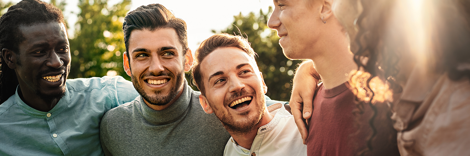 A group of men laughing together outdoors, taking protective measures against mpox in their private lives.