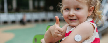 A little girl with childhood diabetes giving a thumbs up while at playing at the park.