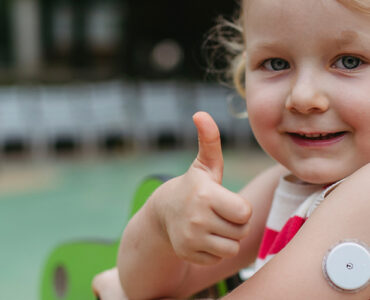 A little girl with childhood diabetes giving a thumbs up while at playing at the park.