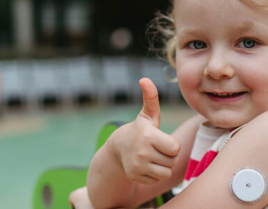 A little girl with childhood diabetes giving a thumbs up while at playing at the park.