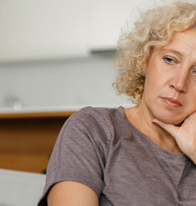 A woman looking melancholy on the coach, dealing with early signs of Huntington's Disease.