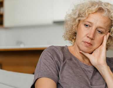 A woman looking melancholy on the coach, dealing with early signs of Huntington's Disease.