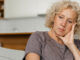 A woman looking melancholy on the coach, dealing with early signs of Huntington's Disease.