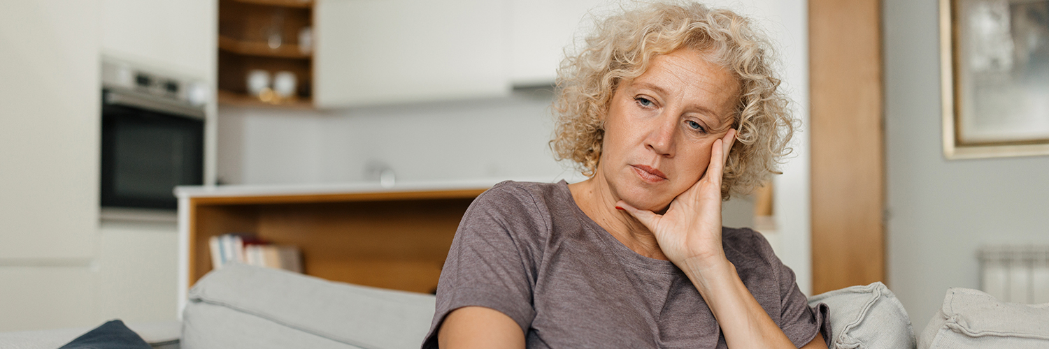 A woman looking melancholy on the coach, dealing with early signs of Huntington's Disease.