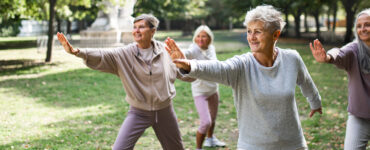 A group of women in a park doing tai chi together as part of their beginner exercise routine.