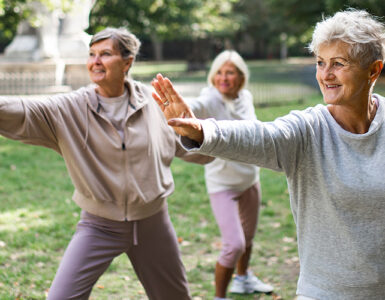 A group of women in a park doing tai chi together as part of their beginner exercise routine.