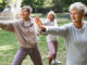 A group of women in a park doing tai chi together as part of their beginner exercise routine.