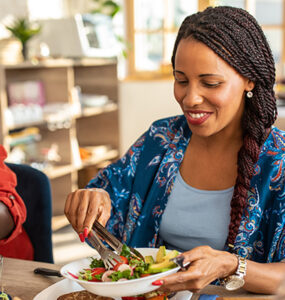 Two women sitting at the table together, eating healthy whole and plant-based foods.